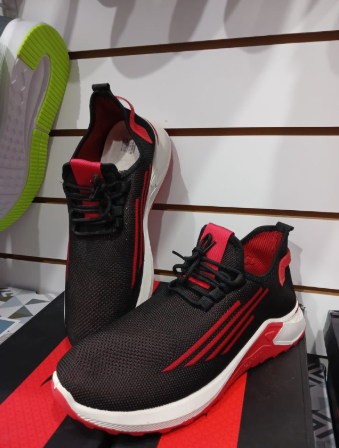 Zapatillas negras en una caja roja. Se ve otro zapato con suela verde.