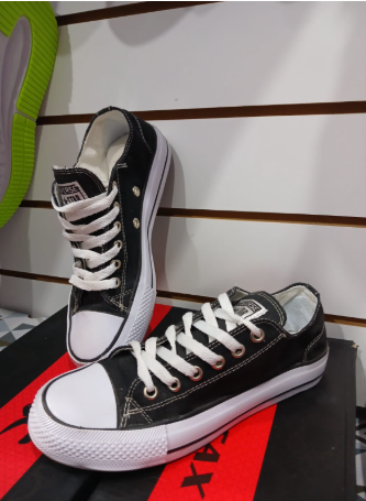 Zapatillas de lona en blanco y negro con cordones blancos, expuestas en el estante de una tienda.