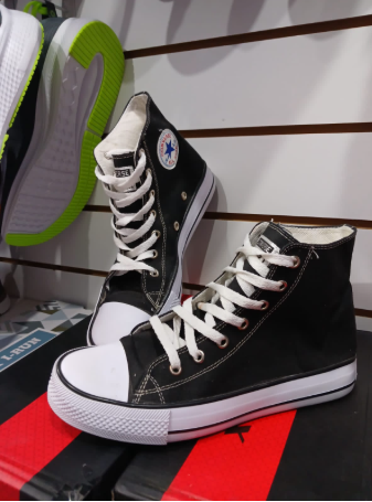 Zapatillas de lona en blanco y negro con cordones blancos, expuestas en el estante de una tienda.