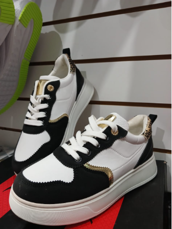 Zapatillas color crema con suela blanca. Se encuentran en una tienda, sobre una caja.