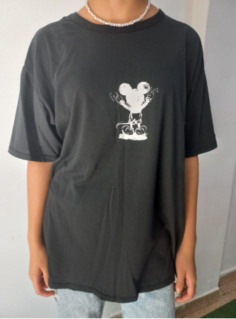 Persona con camiseta negra y un personaje de dibujos animados blanco. Lleva un collar de cuentas blancas.