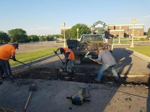 A group of people are digging in a parking lot in front of a mcdonald 's
