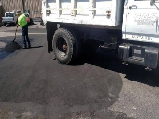 A man with a broom is standing next to a dump truck