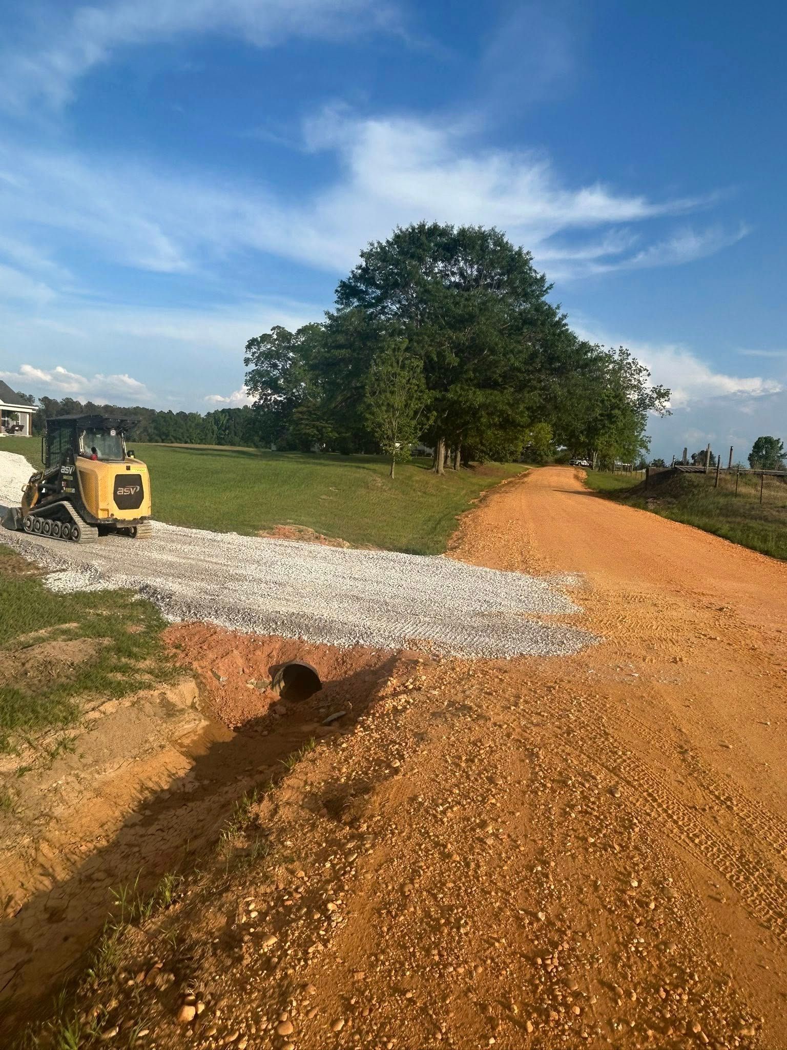 A tractor is driving down a dirt road next to a field.
