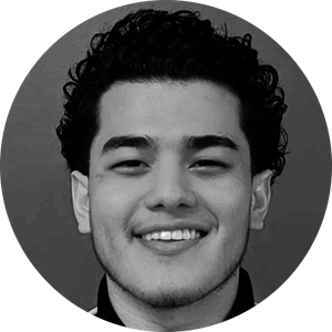 Smiling young man with curly hair in a black and white portrait.