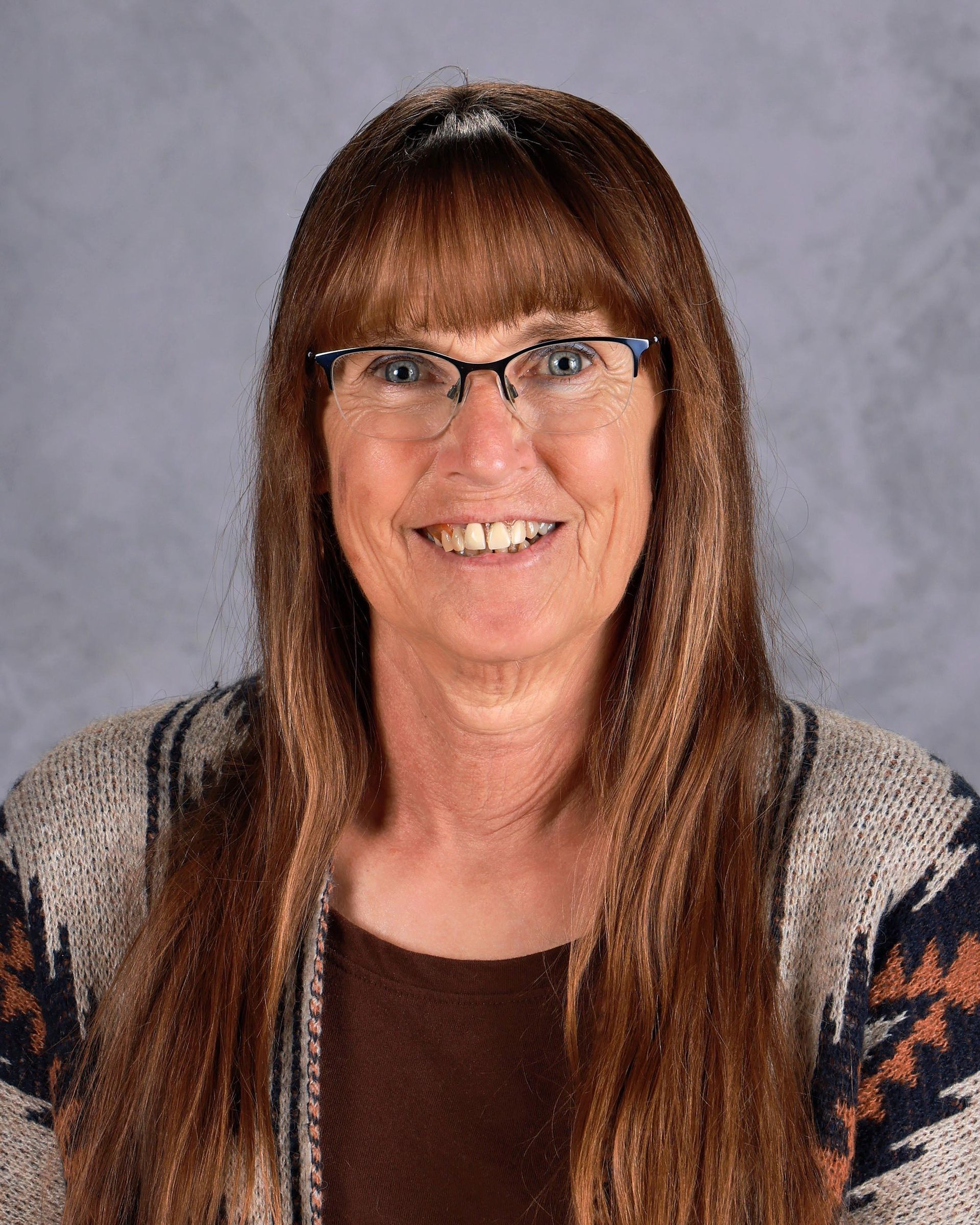 A young woman with long brown hair is smiling for a picture.