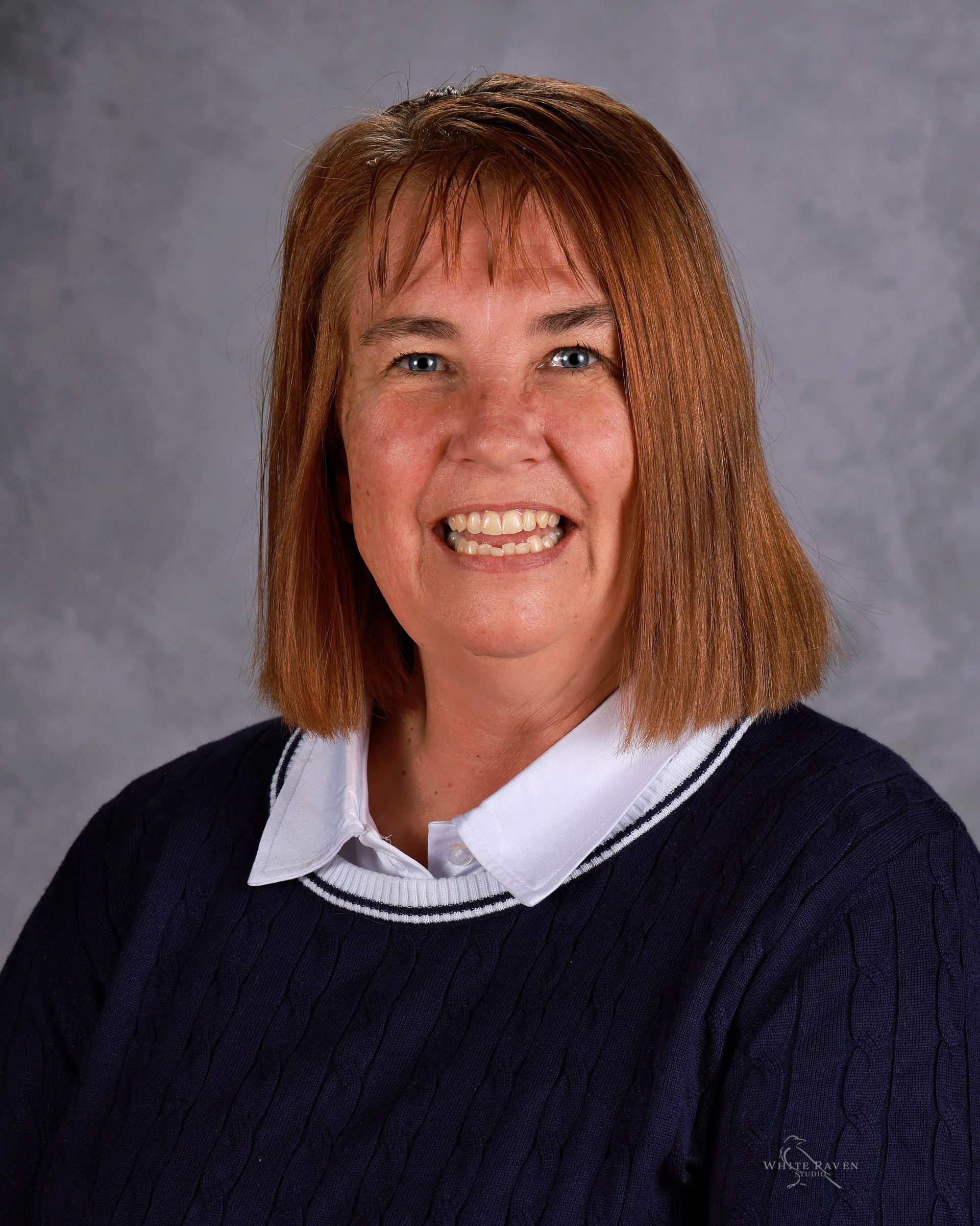 A woman with long brown hair is smiling for a picture.