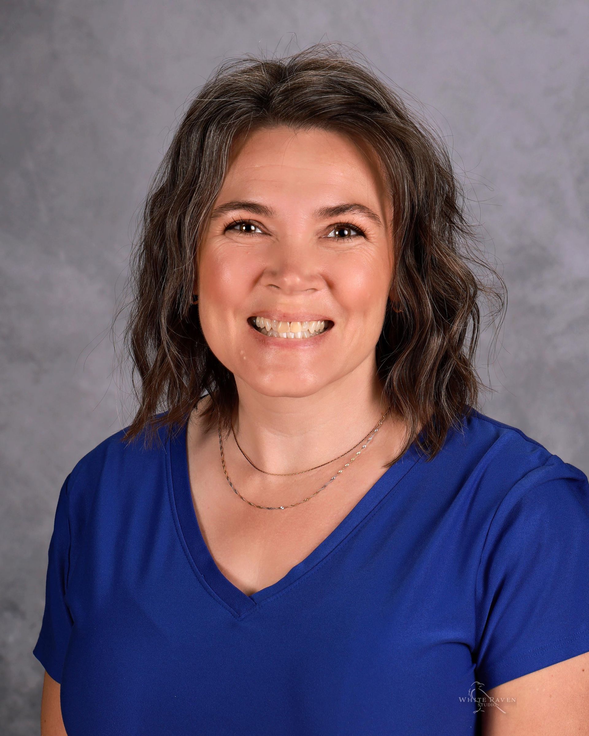 A woman in a floral shirt is smiling for the camera.