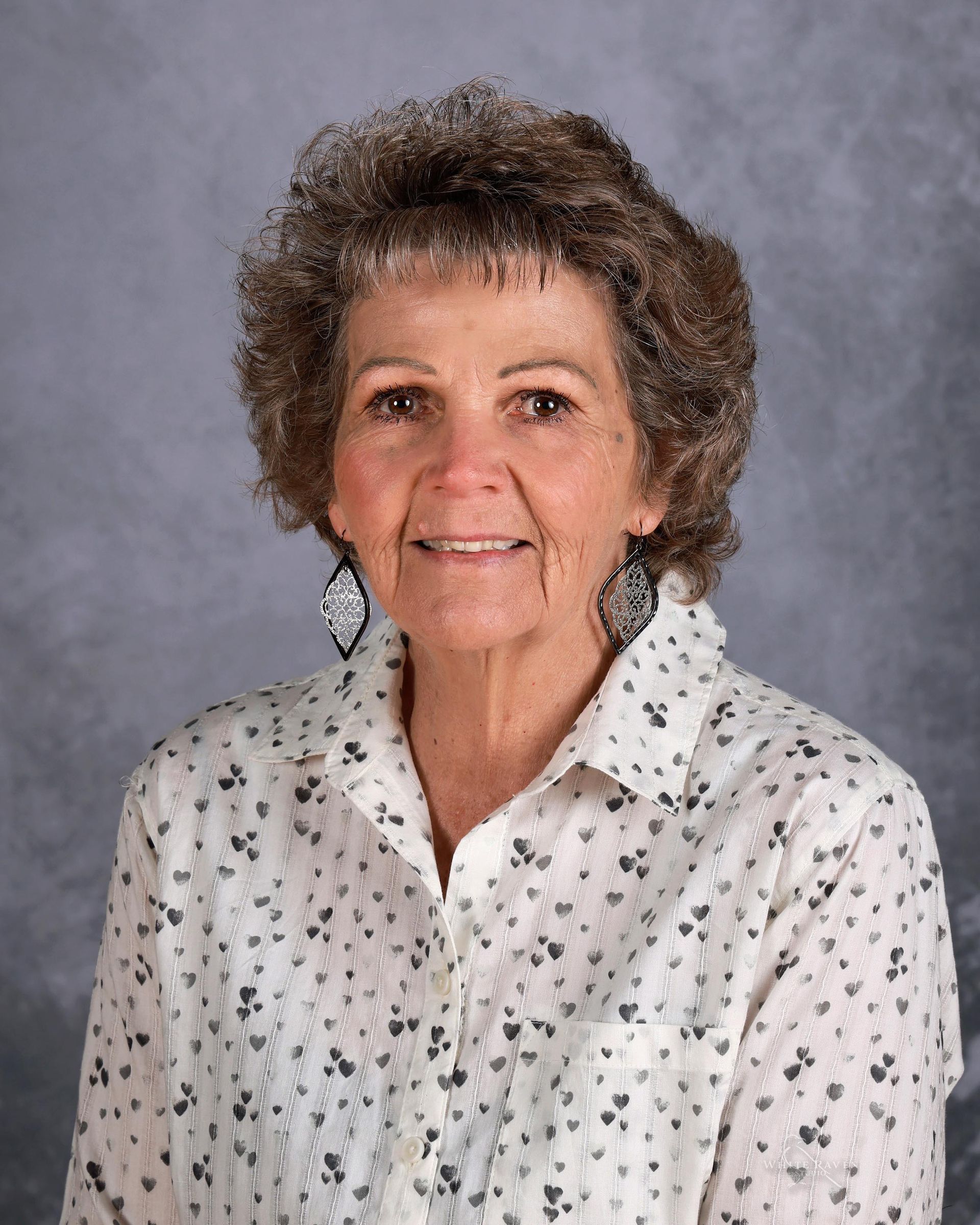 A woman in a pink plaid shirt is smiling for the camera.