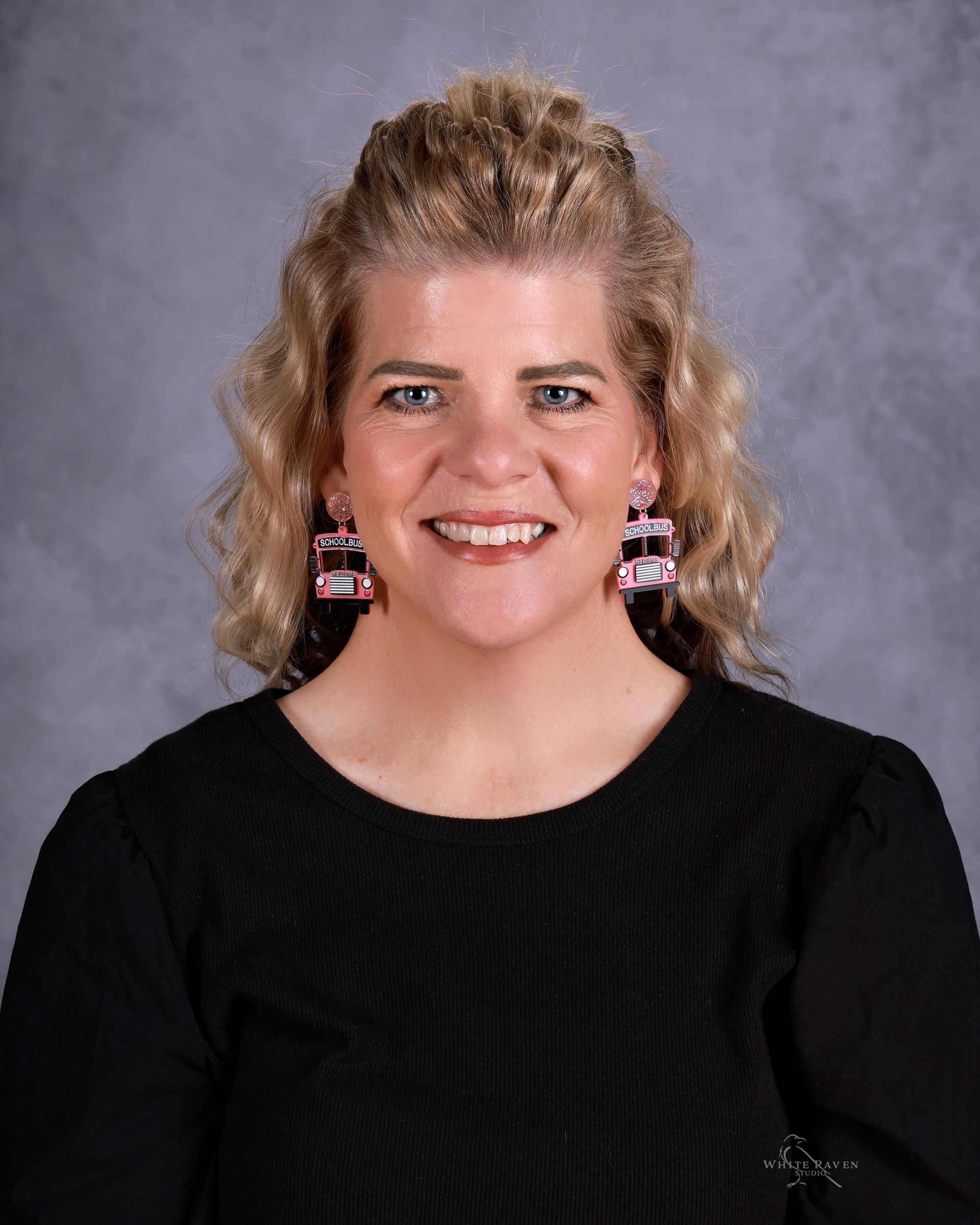A woman in a red shirt is smiling for the camera.