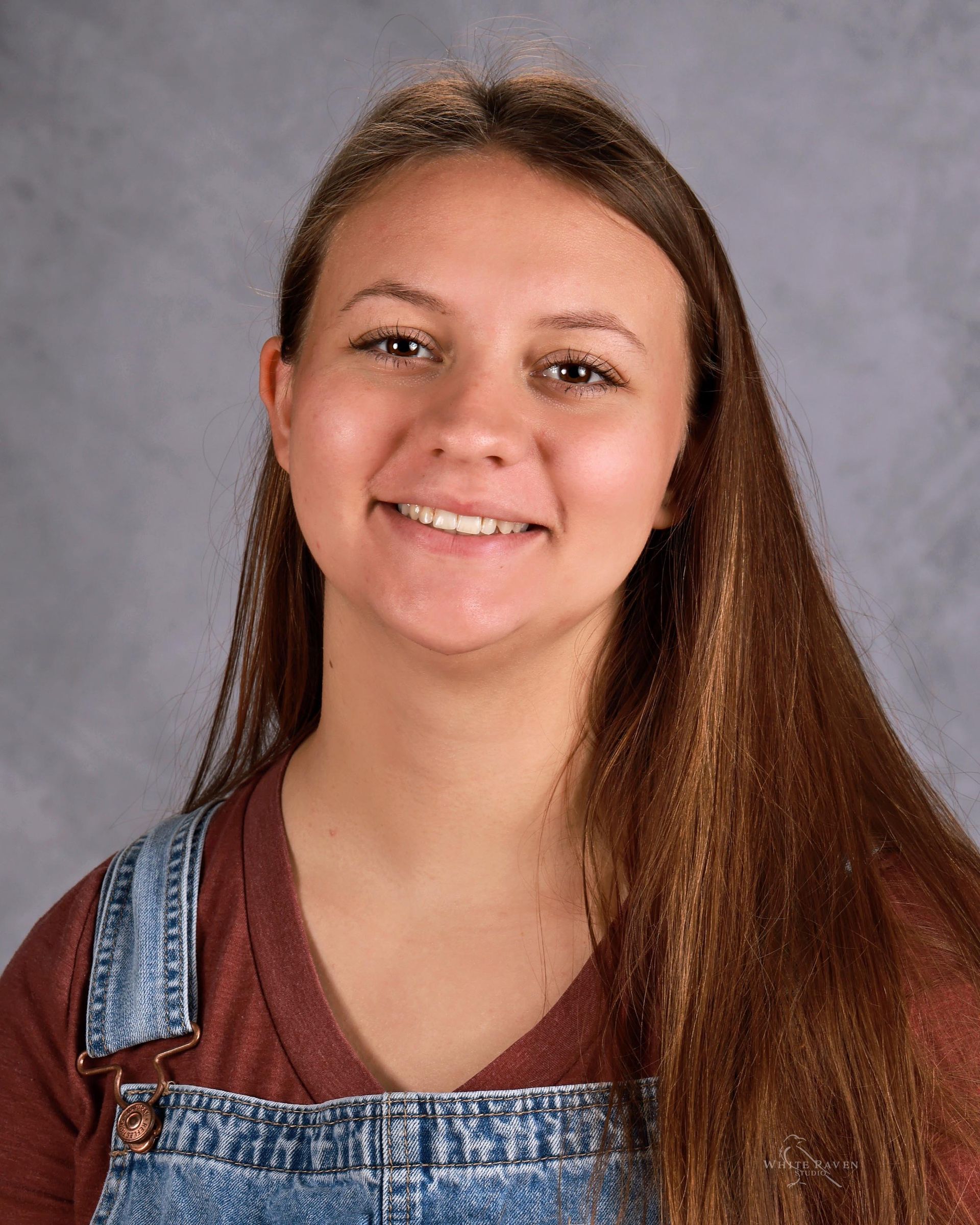 A woman with long brown hair is smiling for the camera.