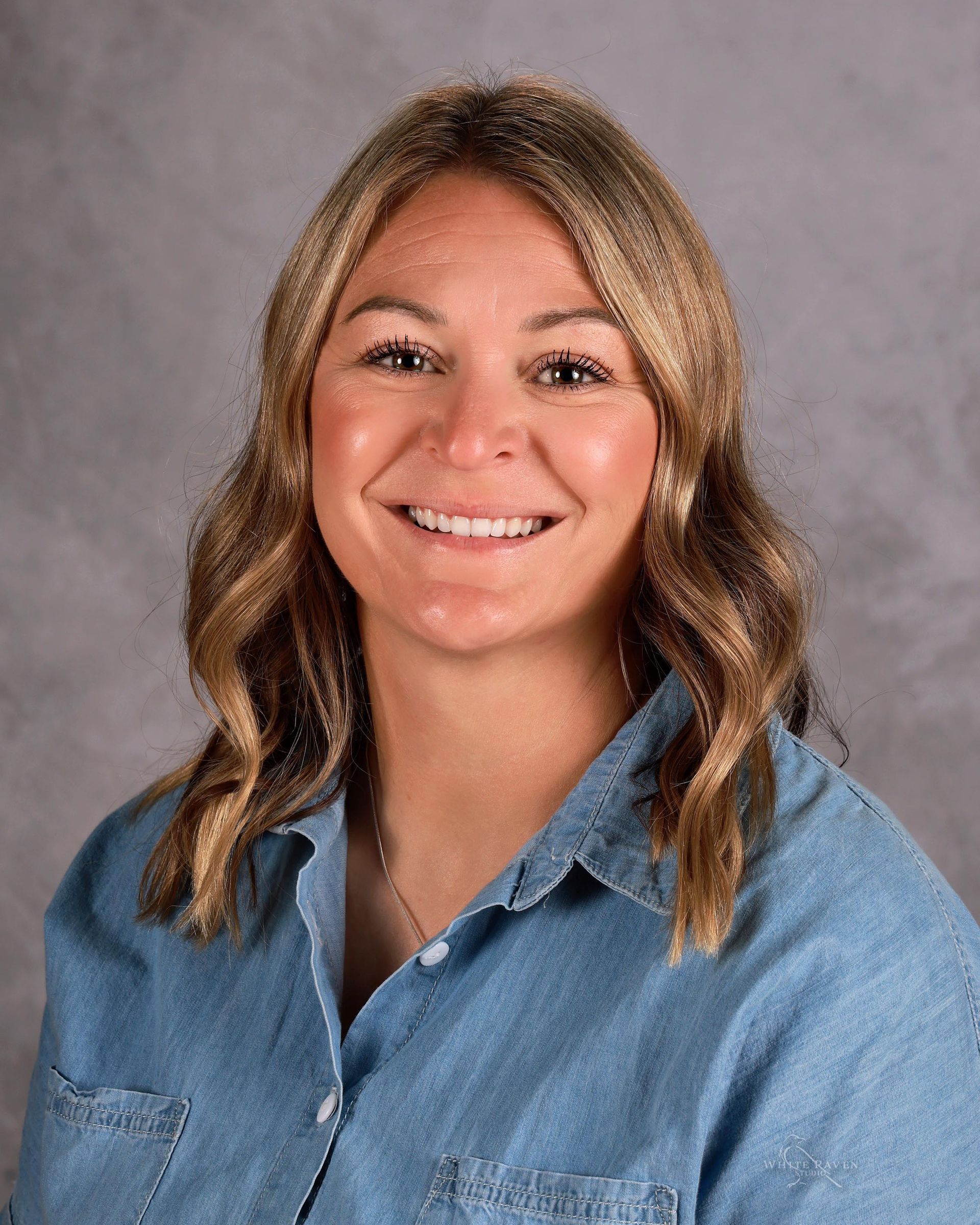 A woman with long blonde hair is smiling for the camera.