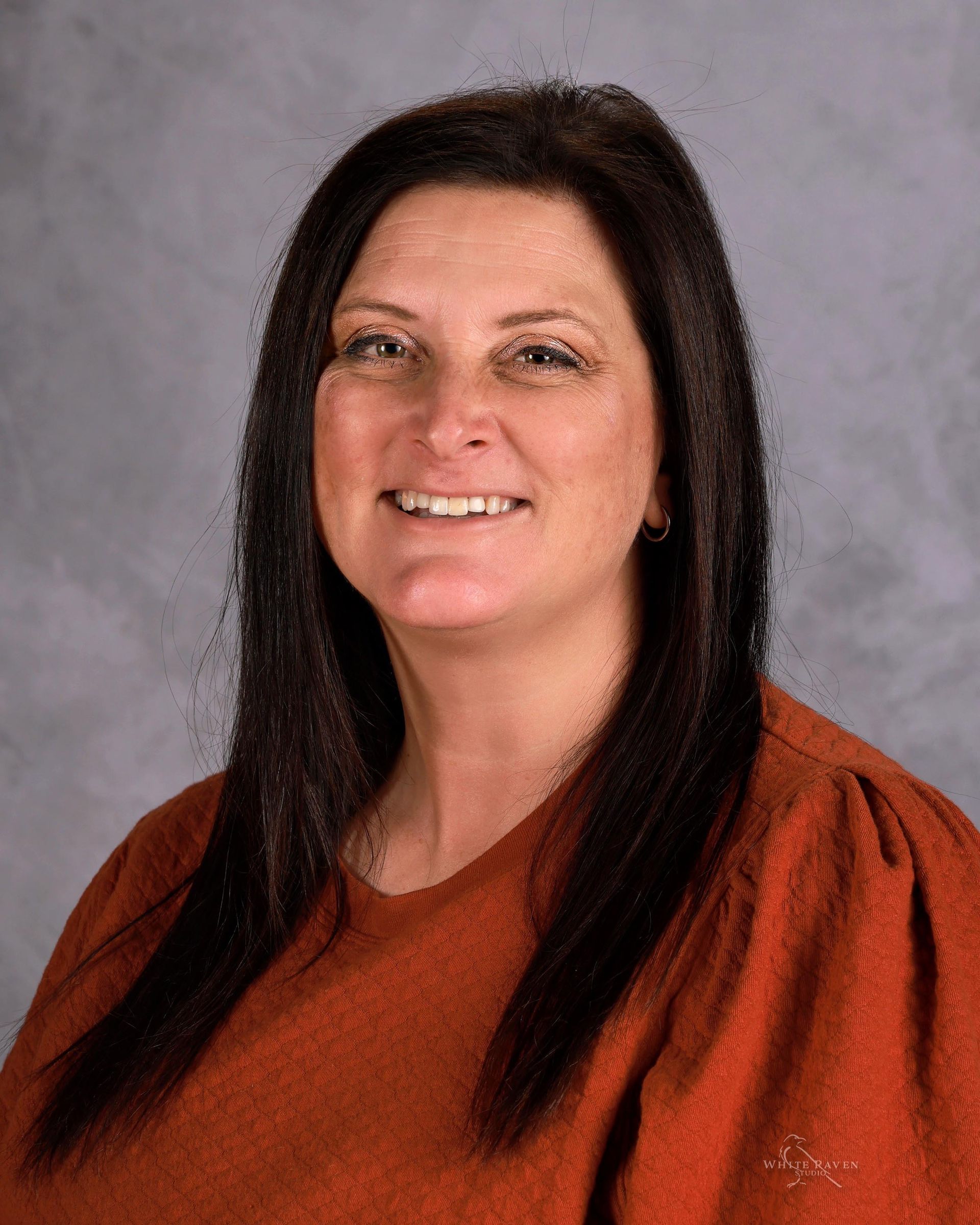 A woman in a green shirt is smiling for the camera.