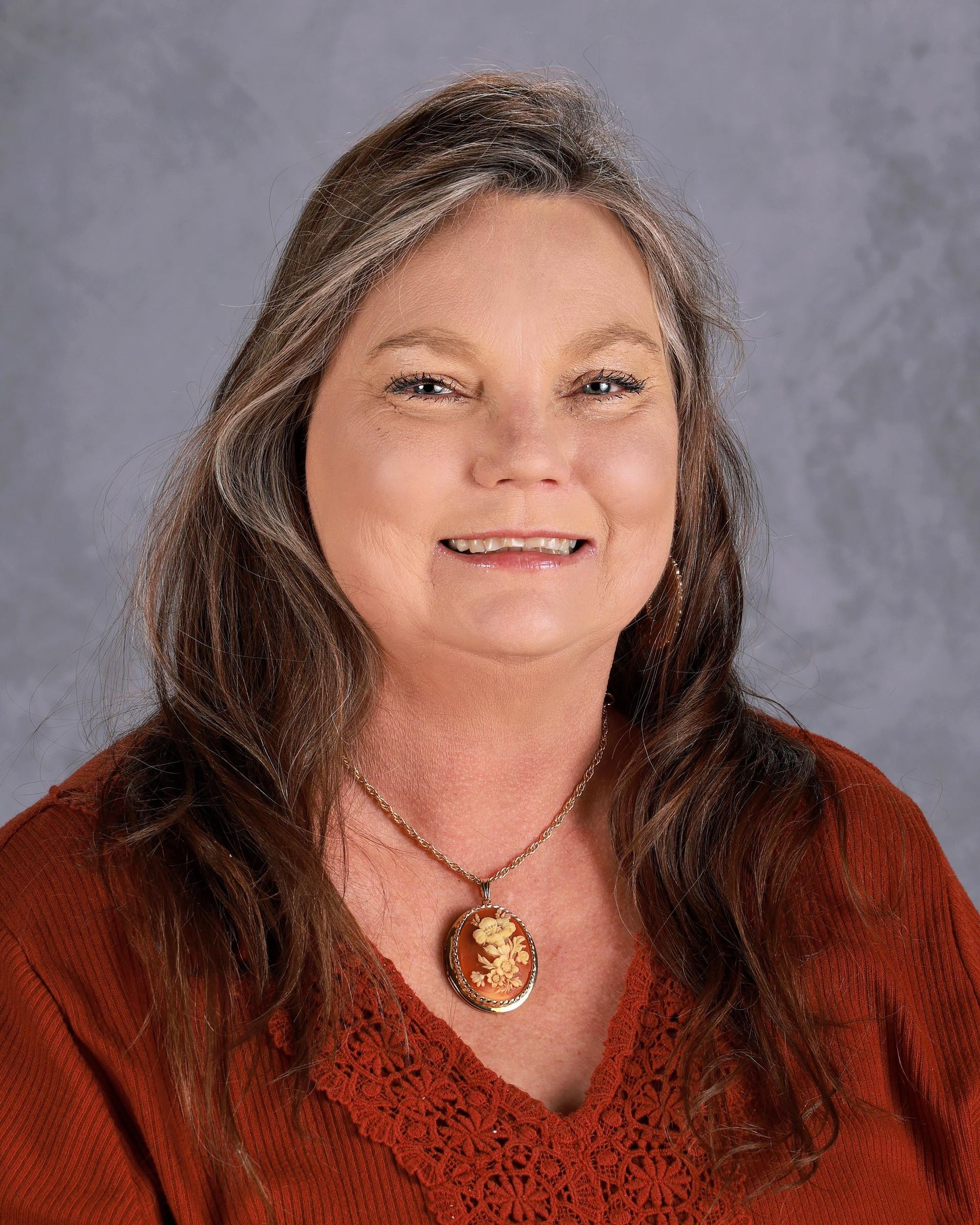 A woman with long hair and hoop earrings is smiling for the camera.