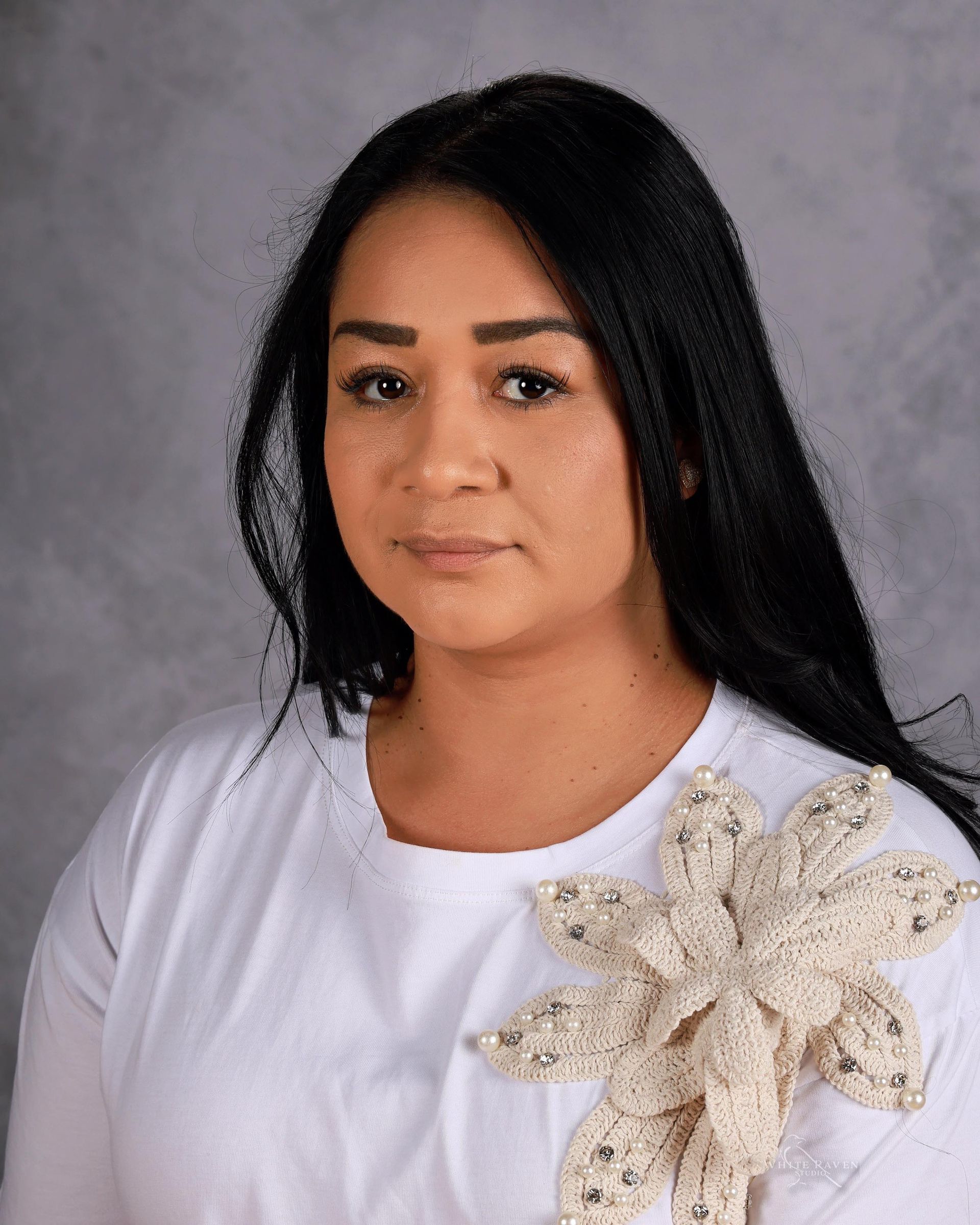 A woman with long black hair is wearing a pink and white striped shirt.
