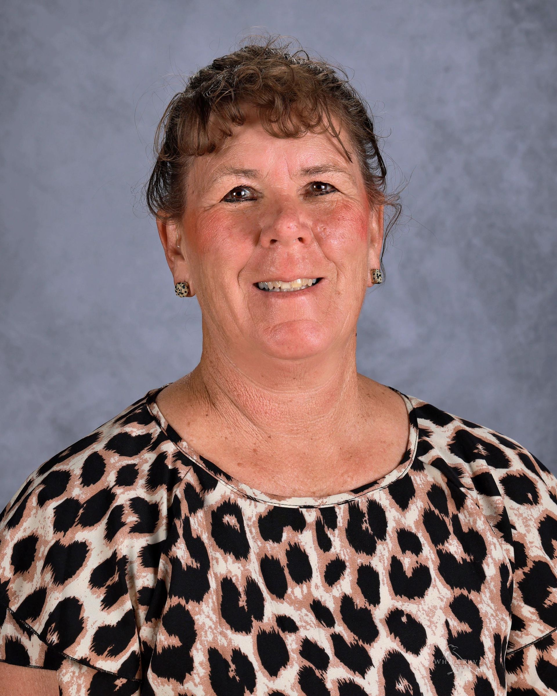 A woman with blonde hair is wearing a black shirt and smiling for the camera.