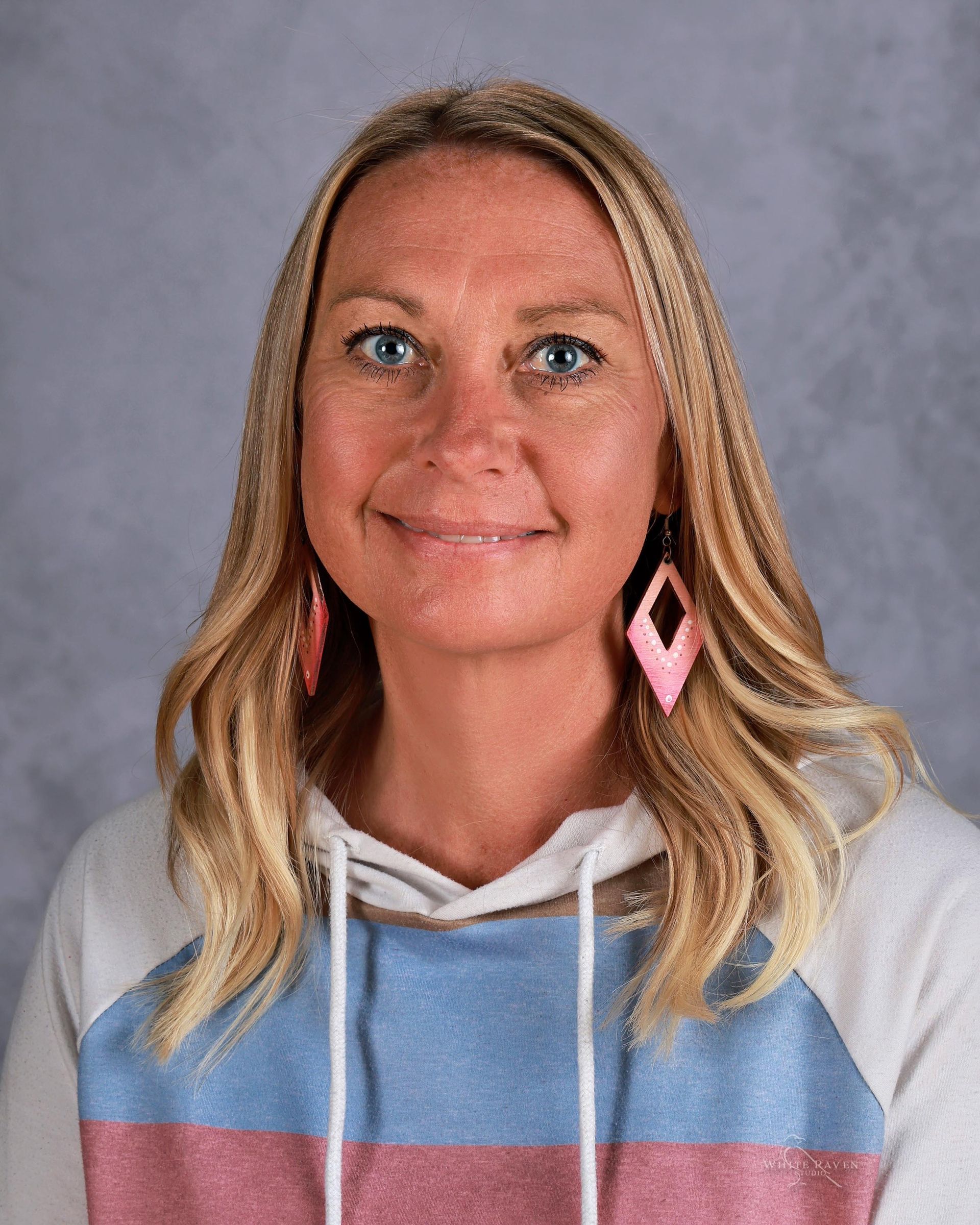 A woman with blonde hair and blue eyes is smiling for the camera.