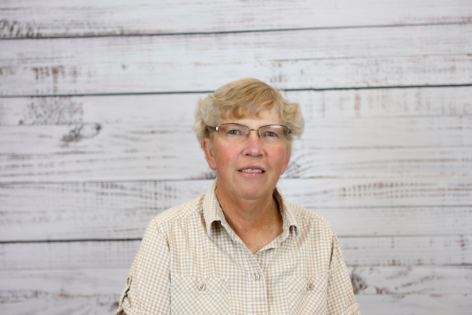 A close up of a woman wearing glasses and a plaid shirt.