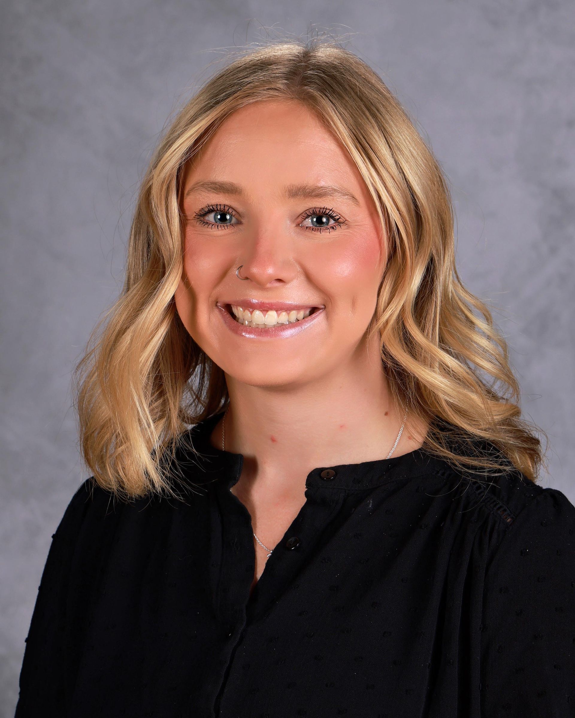 A woman with long brown hair is smiling for the camera.