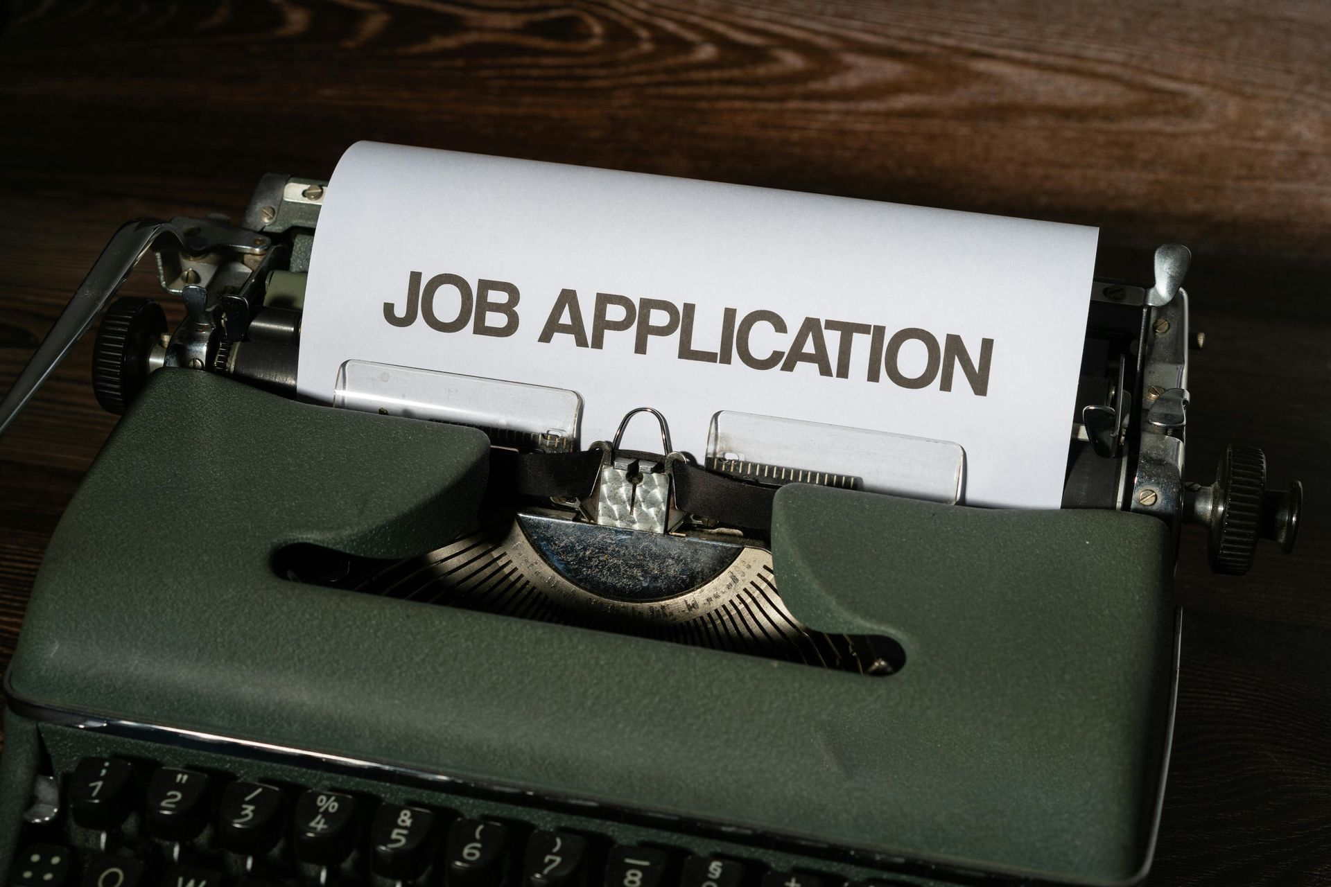 A typewriter with a piece of paper that says job application on it