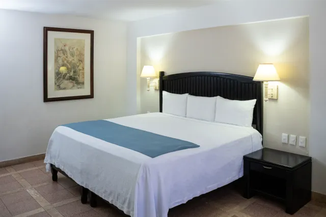 Habitación de hotel con cama, mesita de noche y decoración de pared.