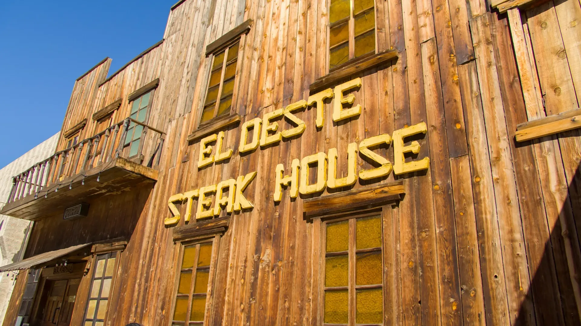 Fachada de madera del restaurante El Oeste Steak House con letras amarillas.