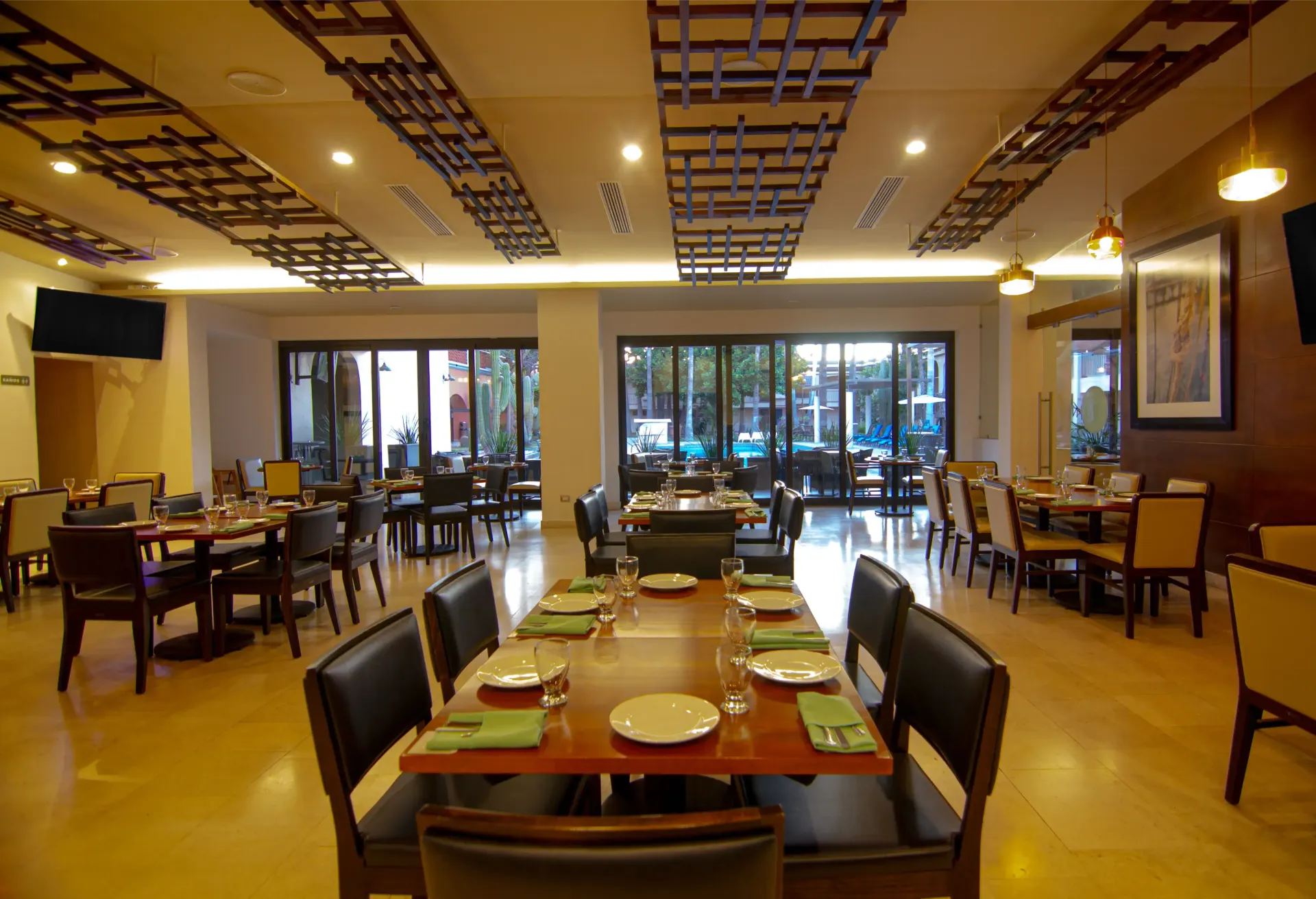 Interior del restaurante con mesas preparadas para comer y vistas al exterior a través de grandes ventanales.
