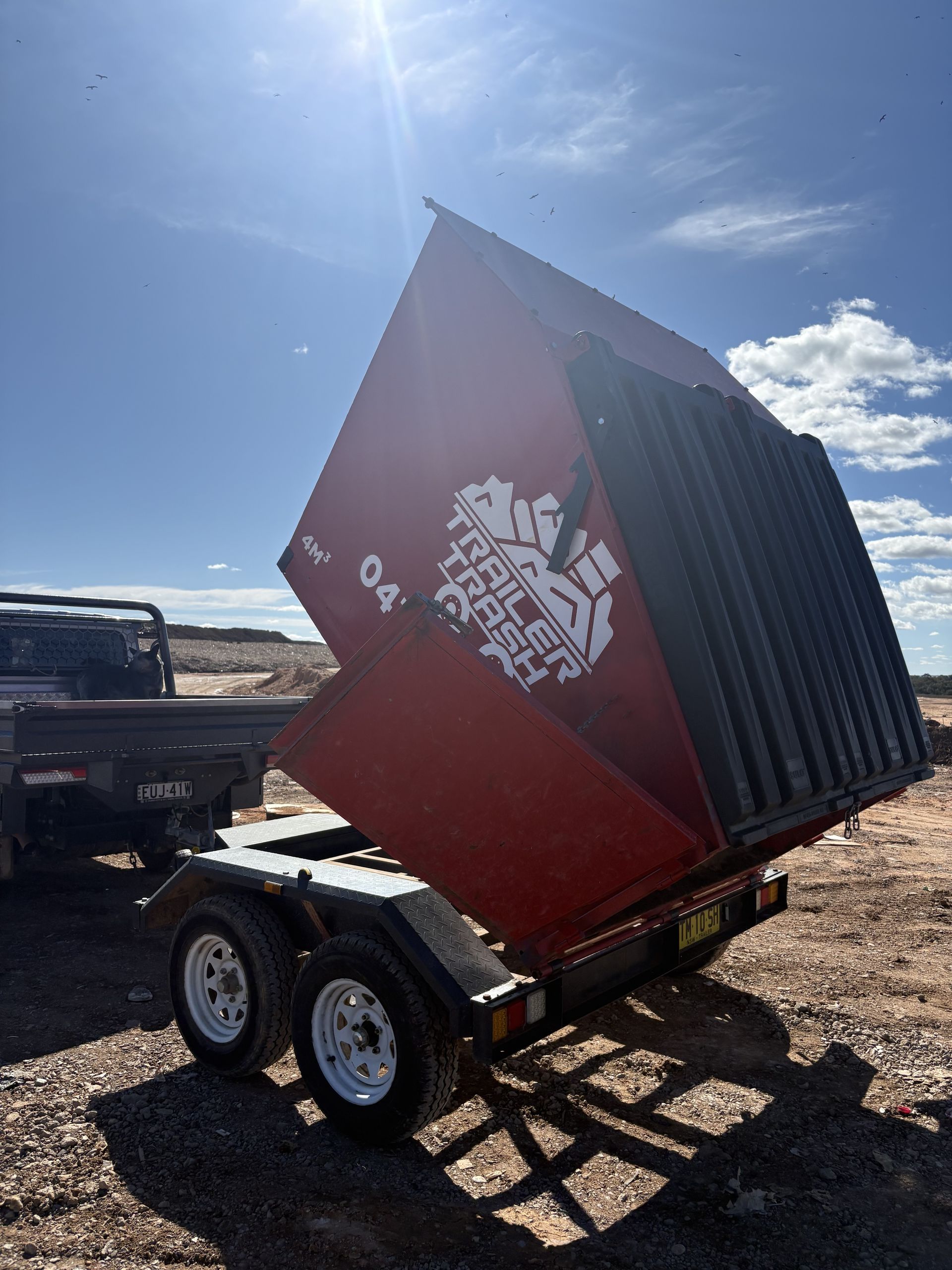 A Red Dumpster Trailer in A Dirt Field— Trailer Trash Dubbo in Dubbo, NSW
