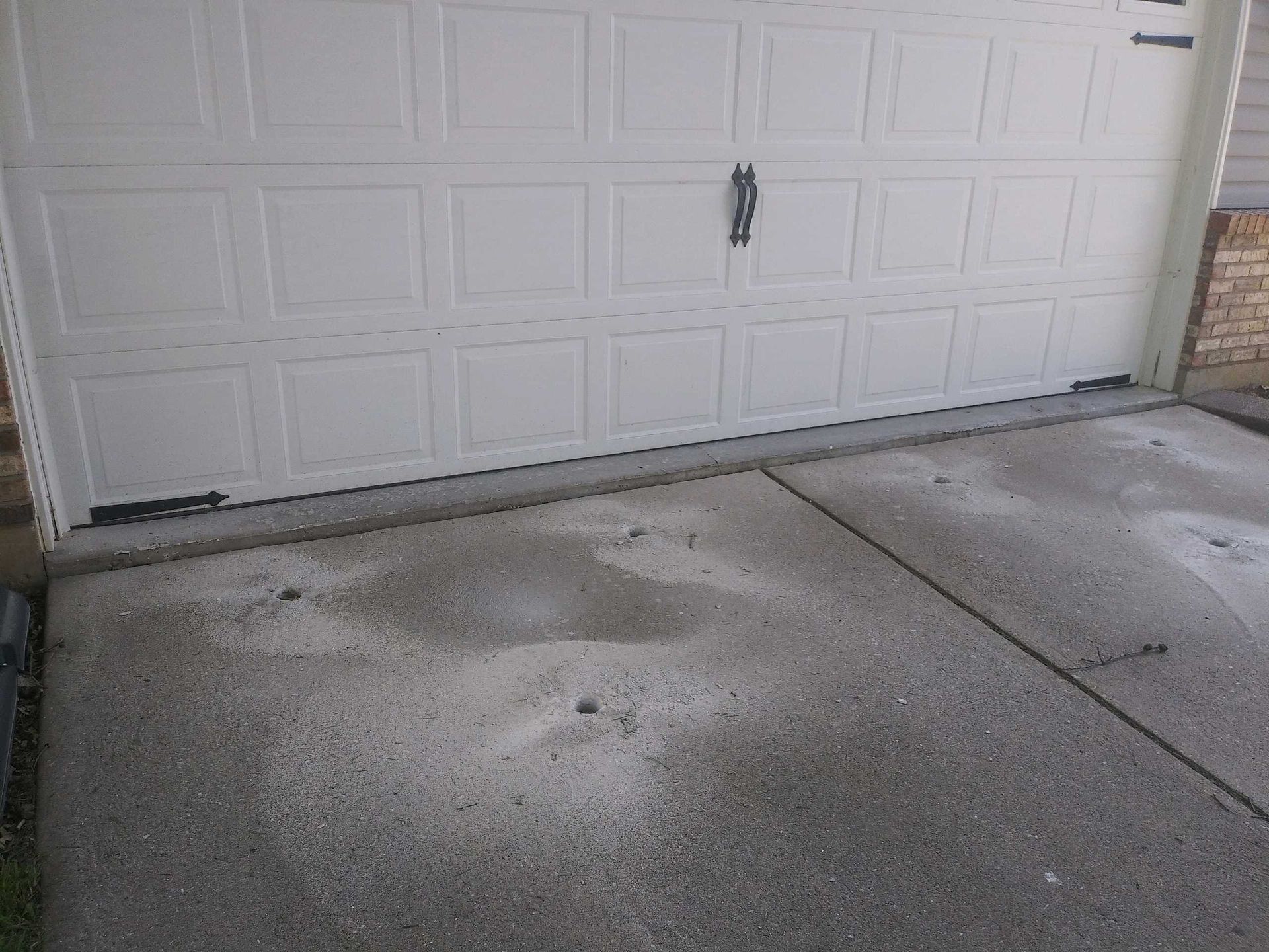 A white garage door is sitting next to a concrete driveway.