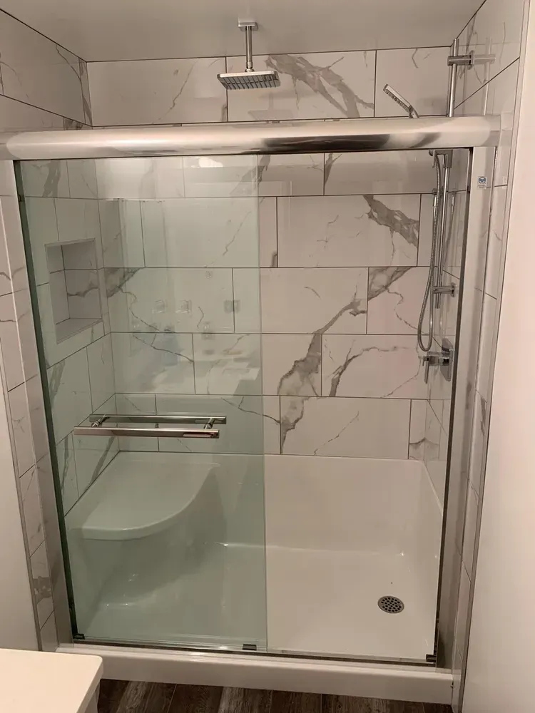 A bathroom with a walk in shower with a sliding glass door.