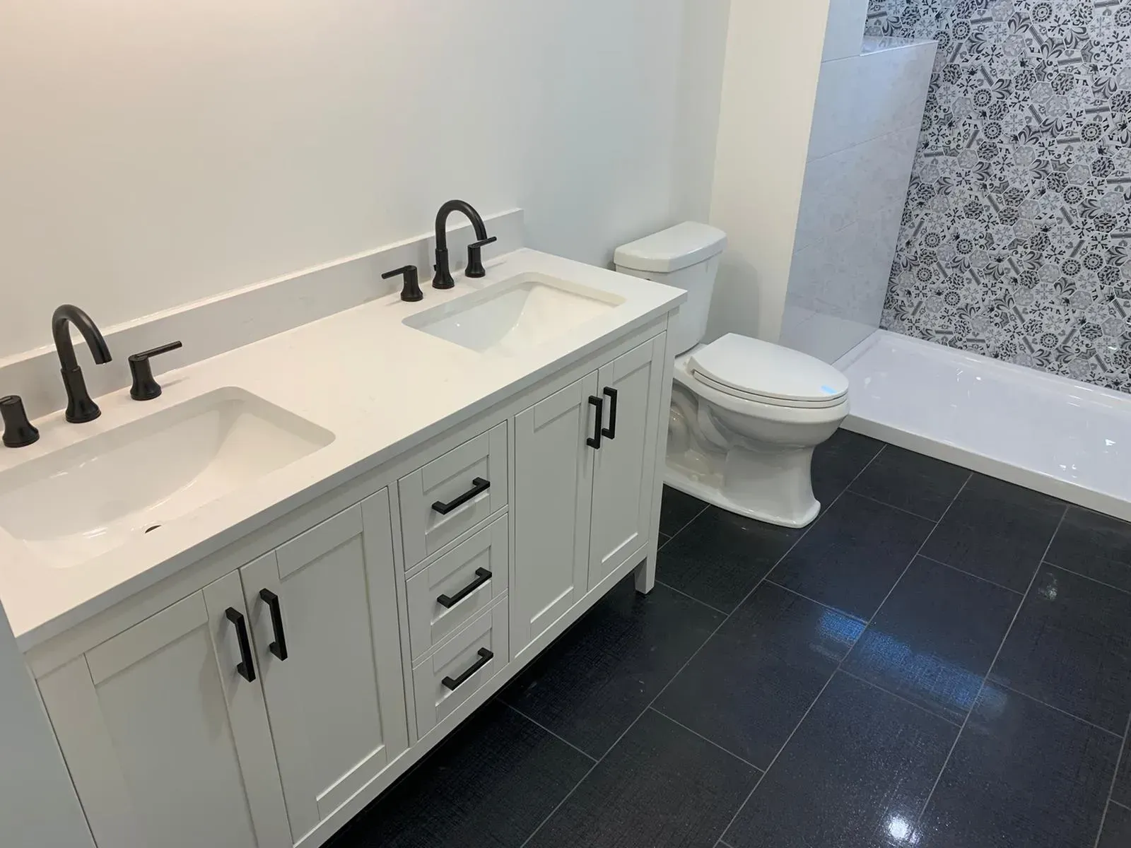 A bathroom with two sinks , a toilet and a shower.