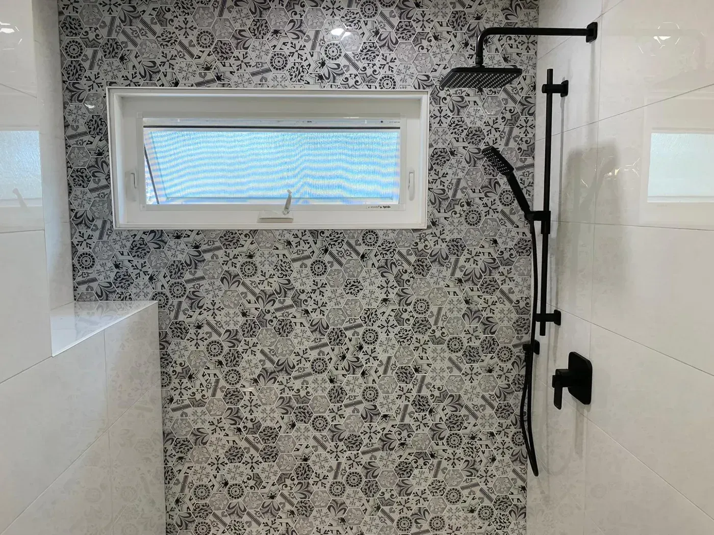 A shower with a window and a shower head.