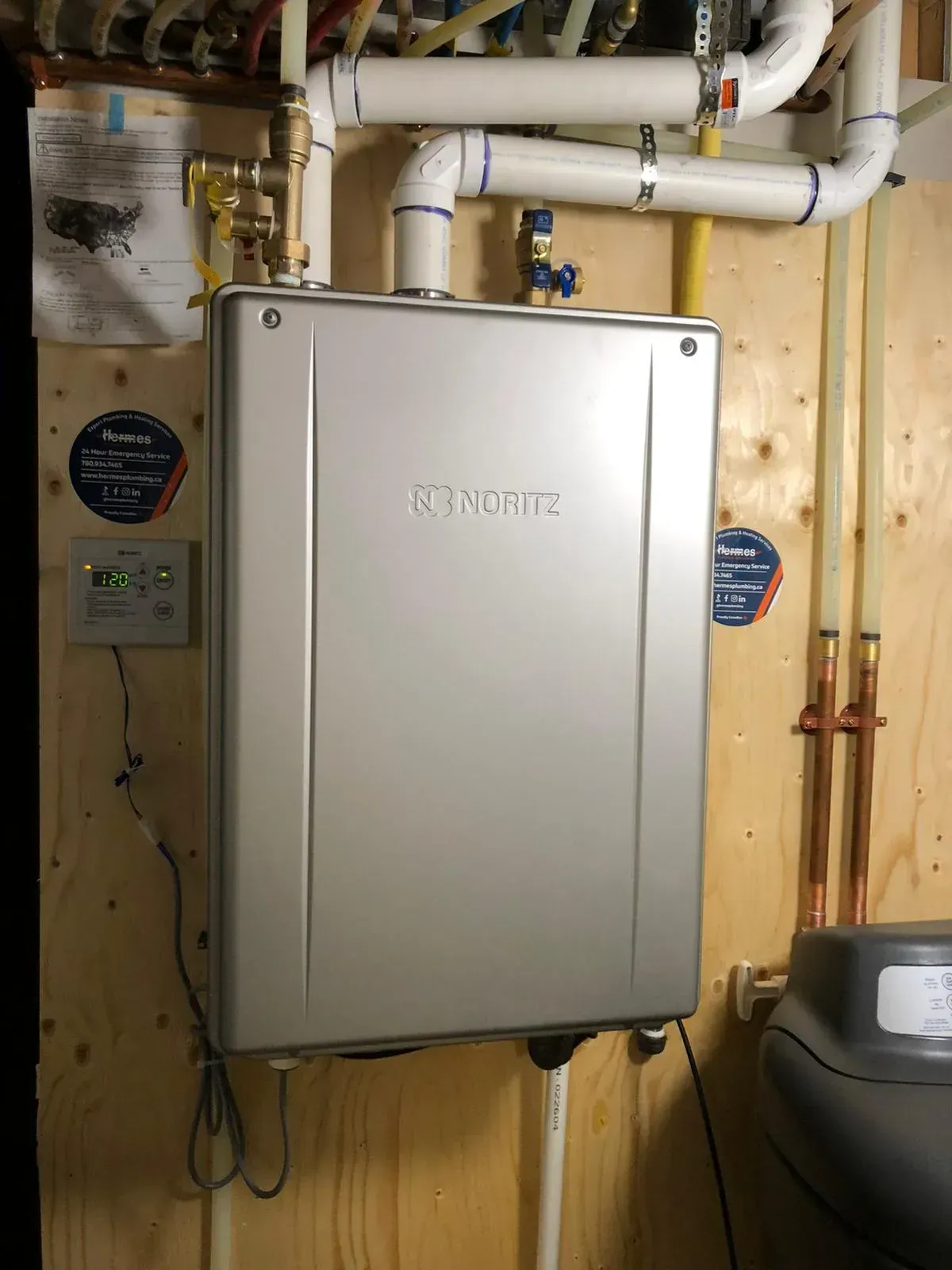 A silver water heater is hanging on a wooden wall.