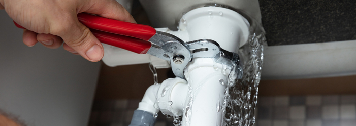 Hermes plumber is fixing a sink pipe with a pair of pliers.