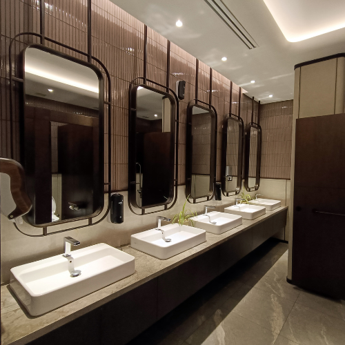 A modern, well-lit restroom featuring five white rectangular vessel sinks, matching chrome faucets, and tall mirrors.