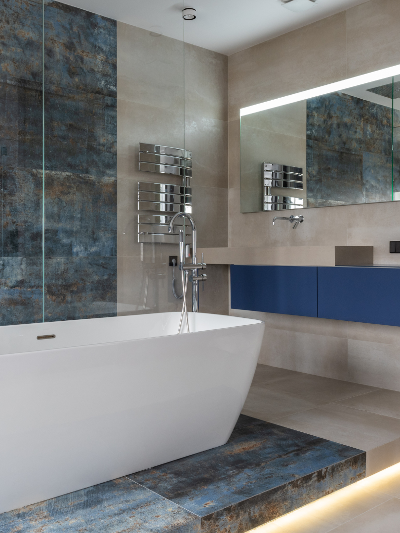 A bathroom with a bathtub , sink , mirror and towel rack.