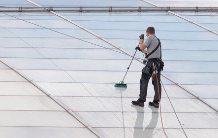 Workers washing the roof made of glass of a modern office building