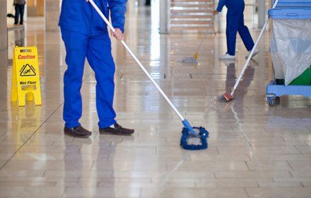 Male cleaners mopping in office atrium