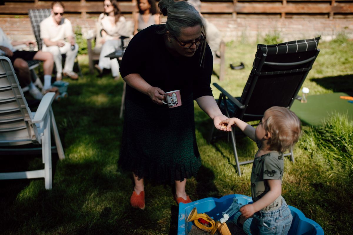 Samen met oma spelen in de zandbak tijdens een familieshoot in de tuin