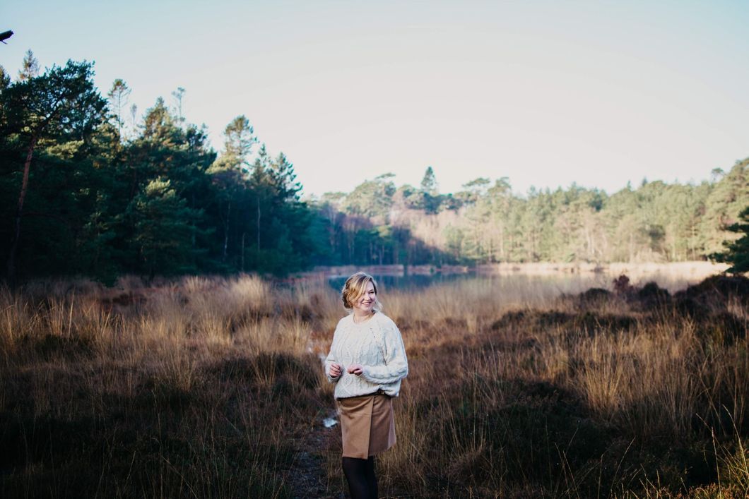 Een vrouw staat in een veld bij een meer