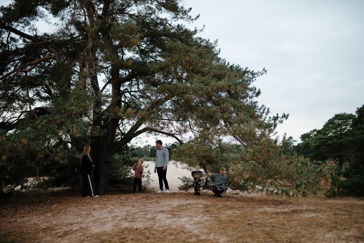 Vijf mensen staan ​​onder een grote, breed uitlopende boom in Appelscha, tijdens een fotoshoot van het gezin