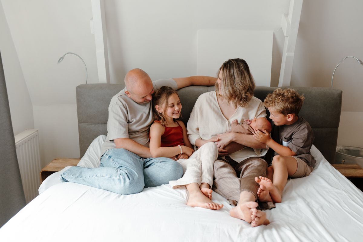 Newbornshoot aan huis, gezin op het grote bed
