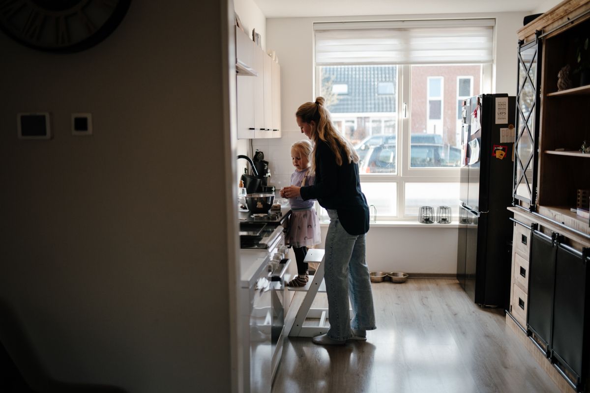 Samen met je dochter koekjes bakken tijdens een fotoshoot. Moeder en dochter staan samen bij het aanrecht. 