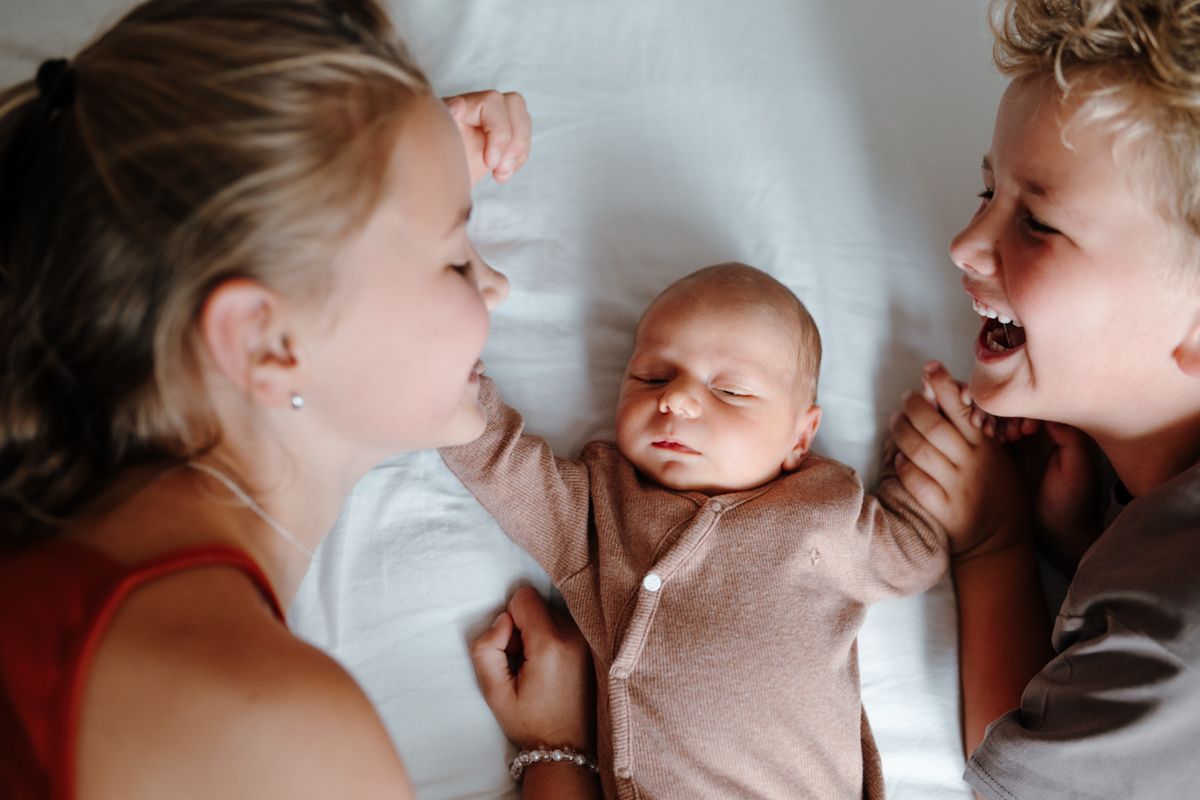 Baby broertje met grotere broer en zus tijdens een newbornshoot in Drenthe