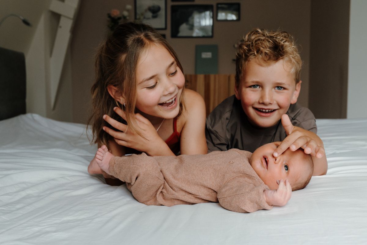 Oudere broer en zus samen met hun broertje op de foto tijdens een newbornshoot