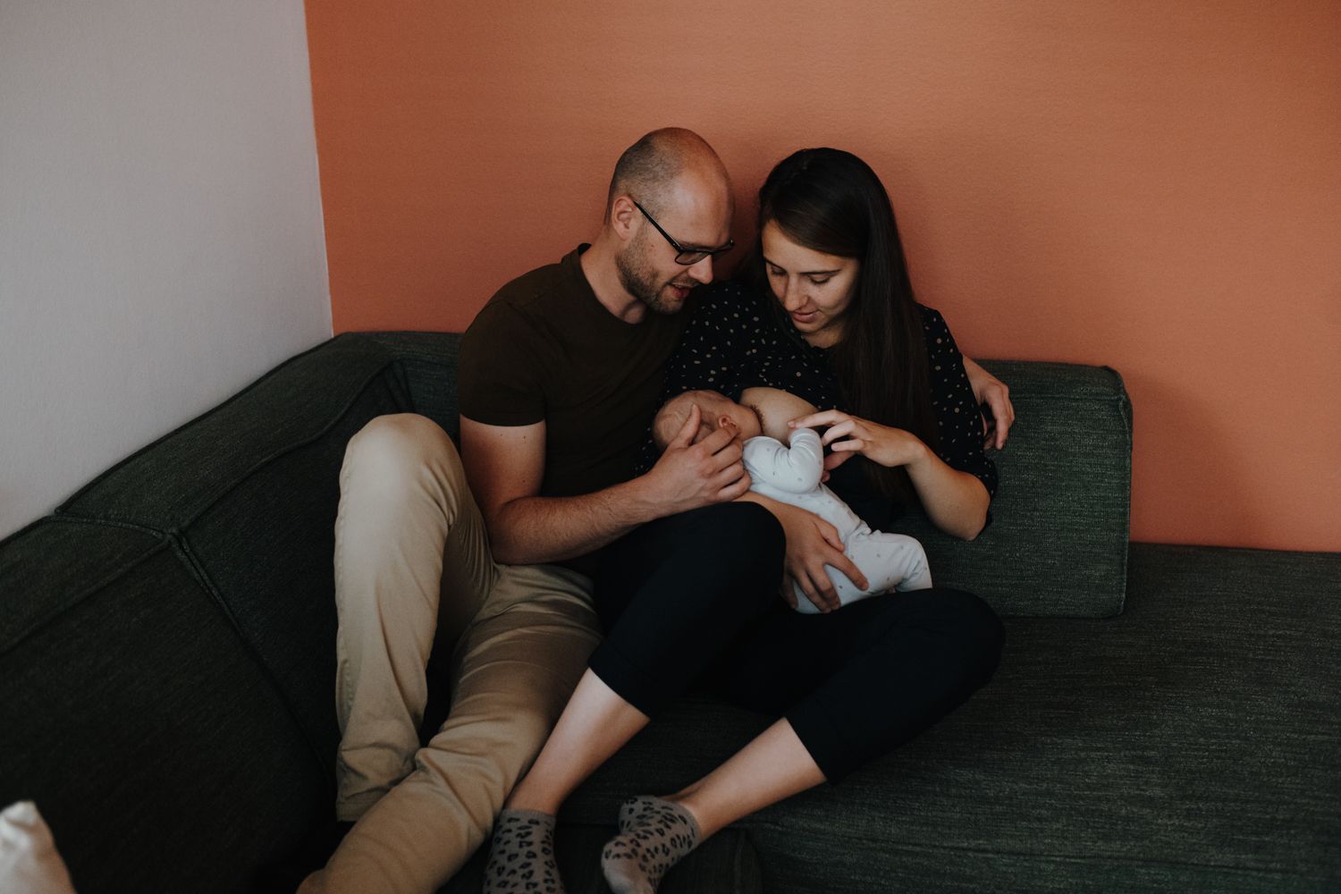 Een man en een vrouw zitten op een bank en houden een baby vast