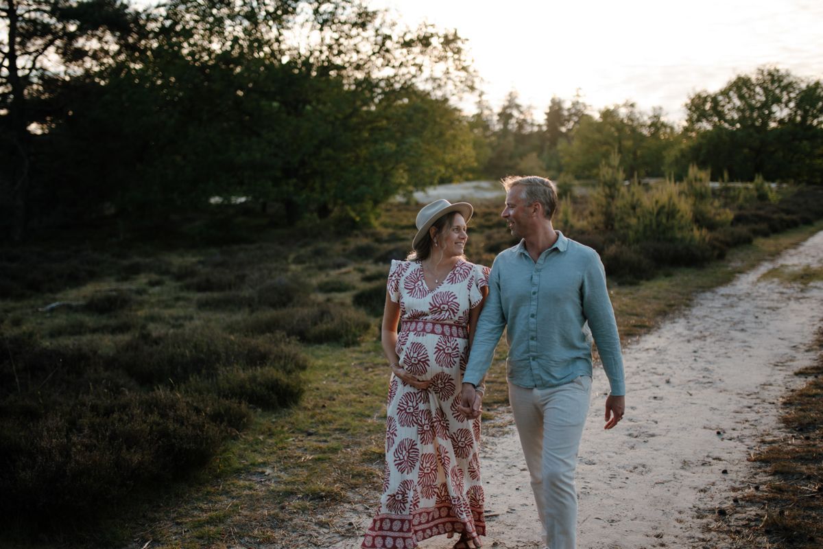 Zwangerschapsshoot lopen op een zandpad 
