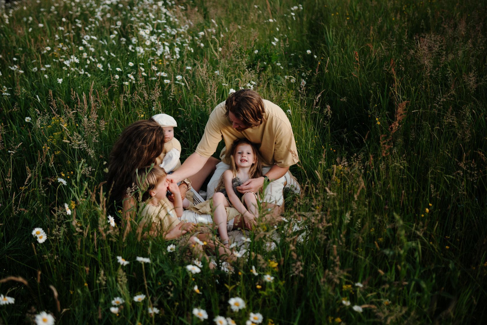 gezin zit in het hoge gras tijdens een gezinsshoot in de natuur
