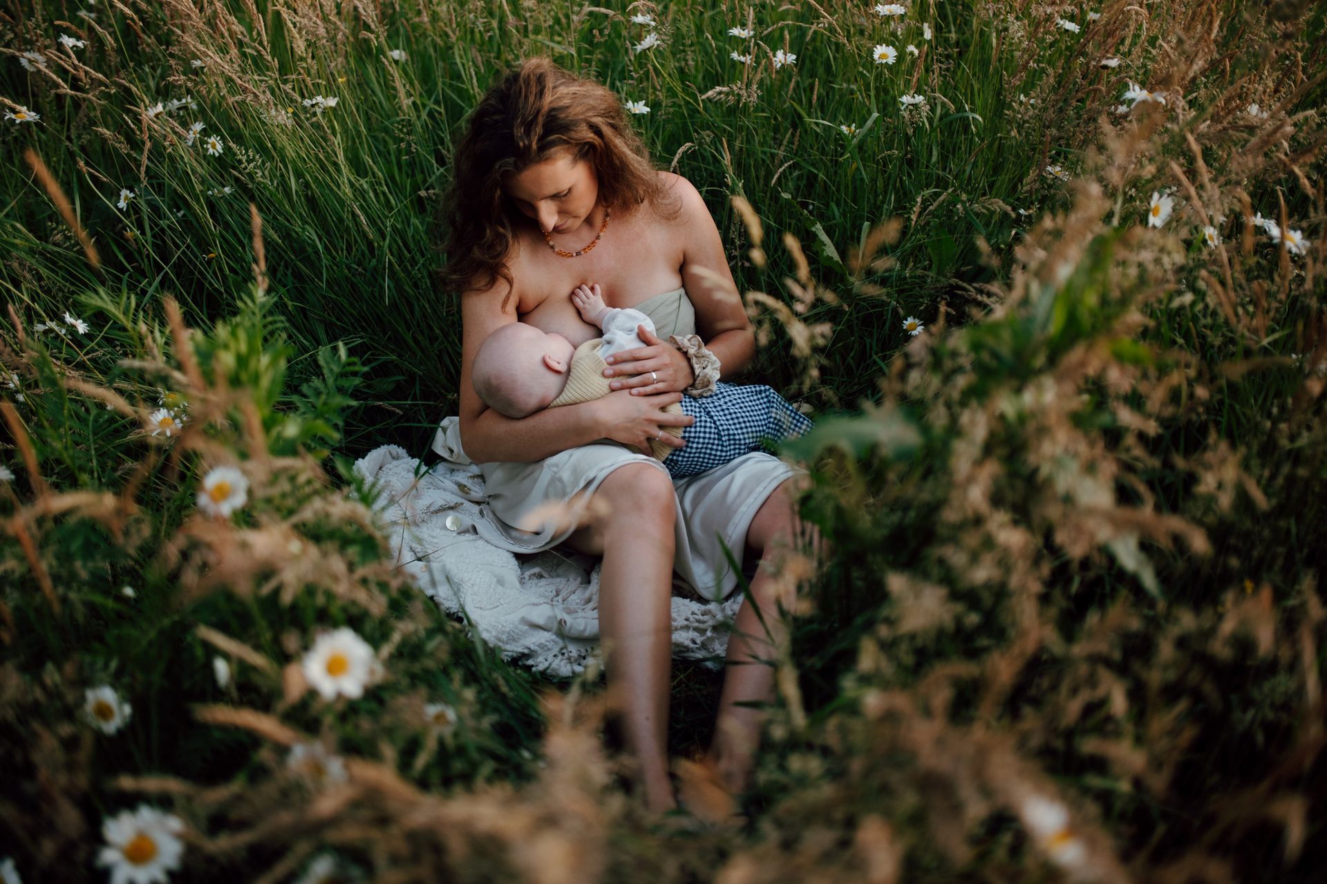 Moeder en zoon in het hoge gras terwijl moeder het kindje voed