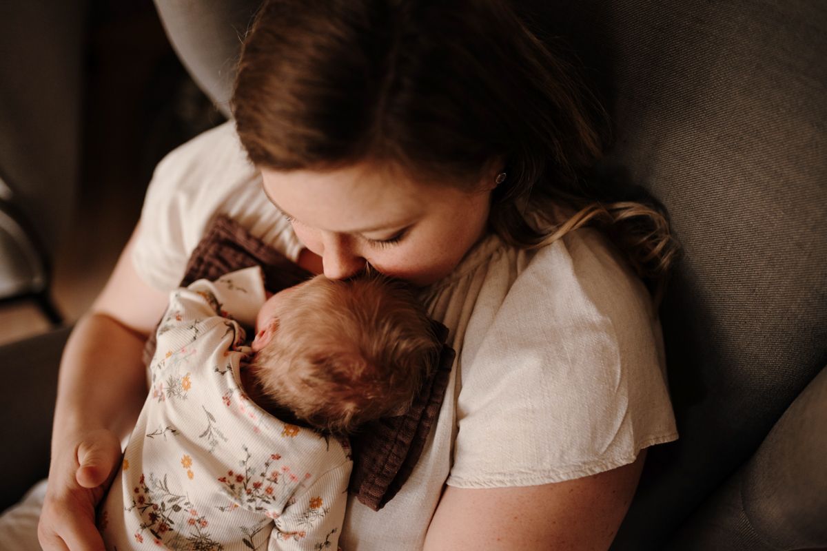 Baby knuffelt met moeder tijdens een fotoshoot bij hun thuis